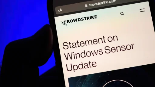 Paris, France - Jul 20, 2024: A male hand holds an iPhone displaying a CrowdStrike webpage with a Statement on Windows Sensor Update, set against a bright blue background, highlighting the company"