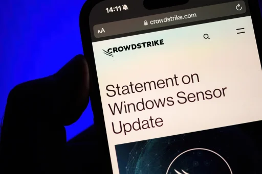 Paris, France - Jul 20, 2024: A male hand holds an iPhone displaying a CrowdStrike webpage with a Statement on Windows Sensor Update, set against a bright blue background, highlighting the company"